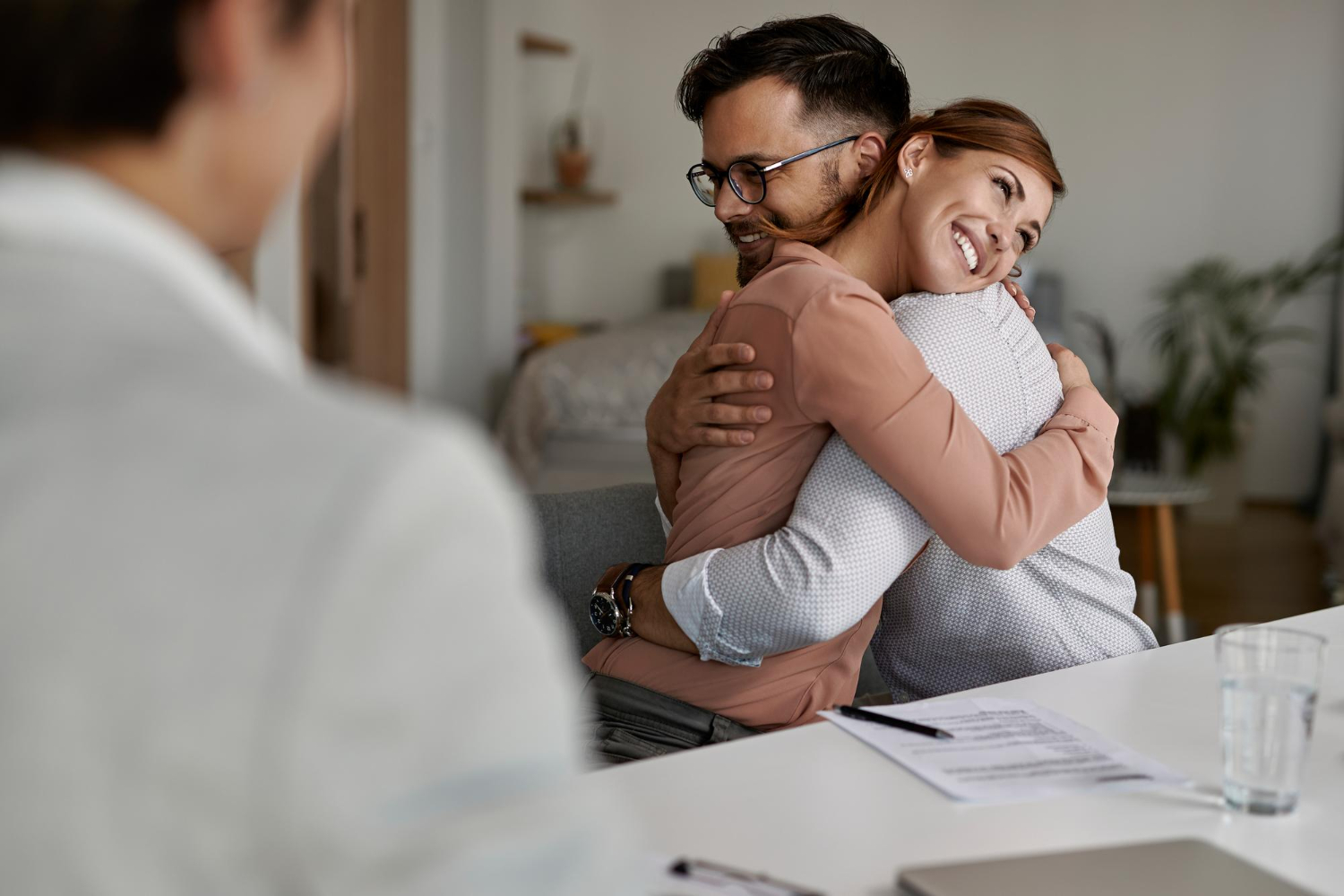 young-happy-couple-embracing-after-successful-meeting-with-their-real-estate-agent